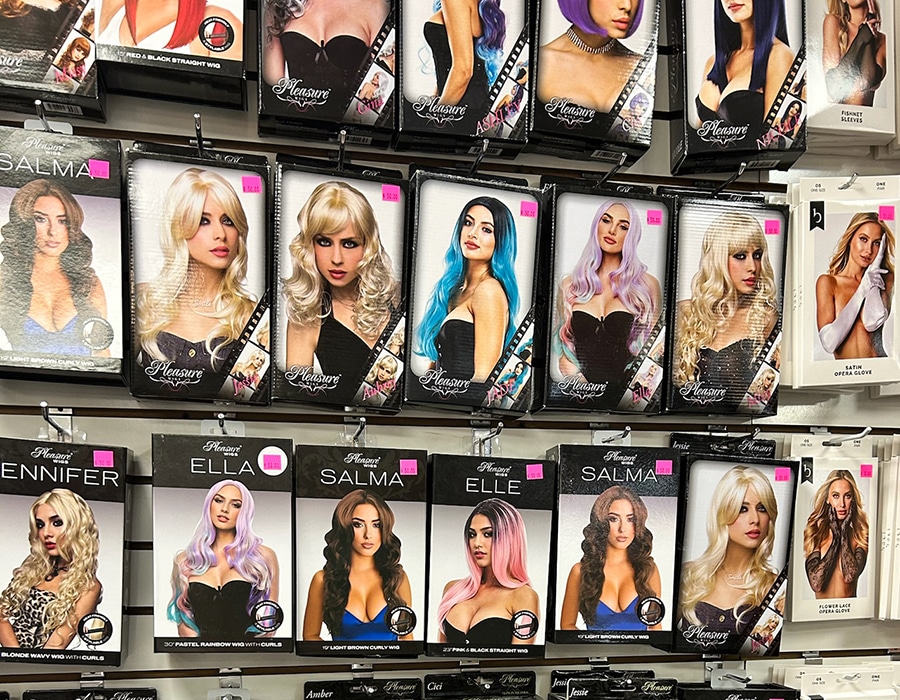 A retail display wall filled with boxes of fashion wigs, each featuring a photo of a model wearing a specific wig style and color.
