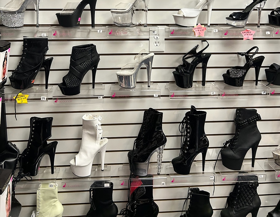 A display wall of various high-heeled platform shoes and boots arranged on shelves.