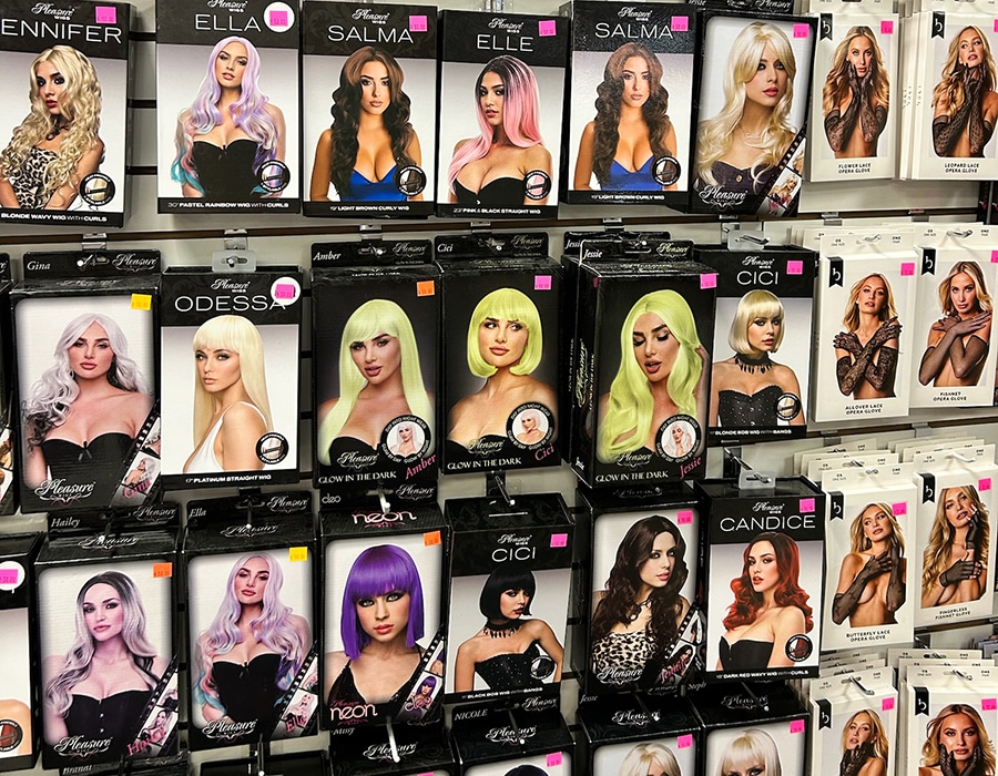 Rows of boxed wigs on display, each featuring a photo of a model wearing a specific style, along with select boxes of opera gloves.