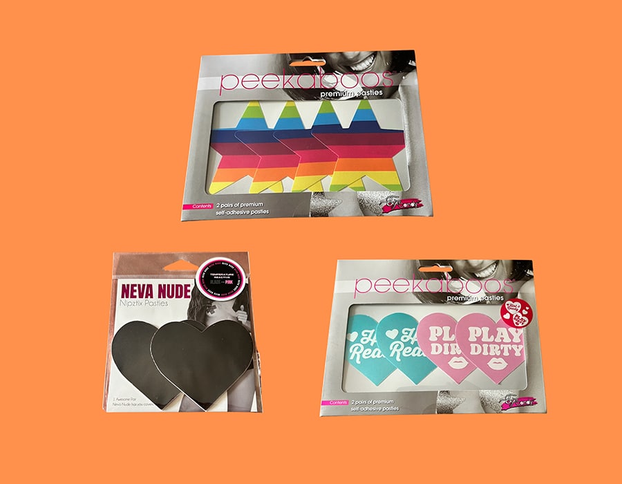 Three packages of adhesive nipple pasties: a top box with rainbow star-shaped pasties, a bottom-left box with black heart-shaped pasties, and a bottom-right box with heart-shaped pasties that say Play Dirty.