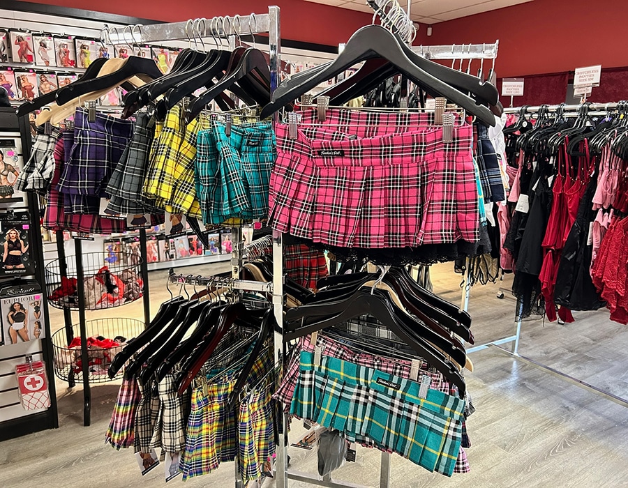 Rows of plaid pleated mini skirts in various colors hanging on clothing racks in a retail store.